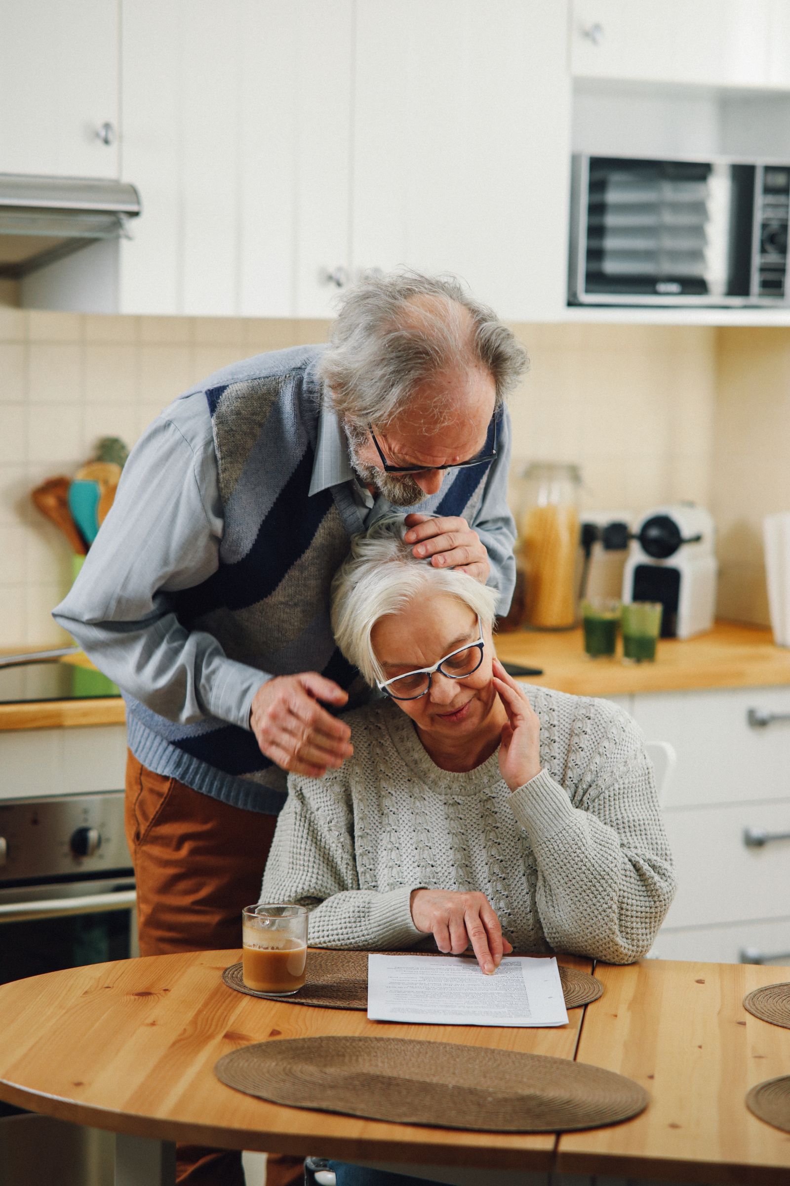 An elderly couple reviewing paperwork together at their kitchen table